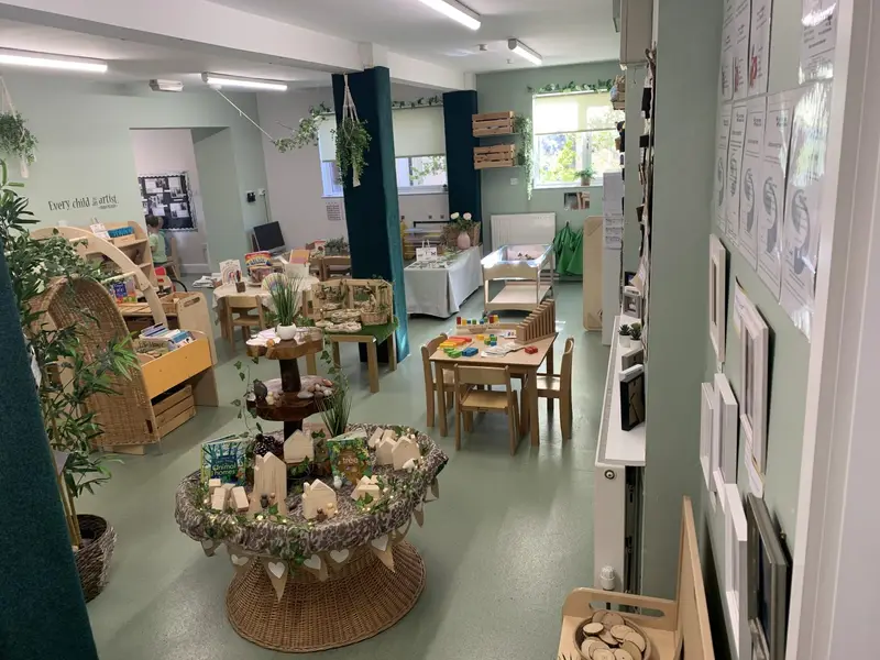 Bright nursery playroom with wooden tables, plants and learning areas at Nursery Rhymes Broughty Ferry